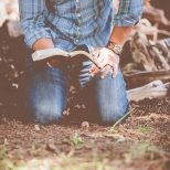 homme à genoux avec une Bible ouverte